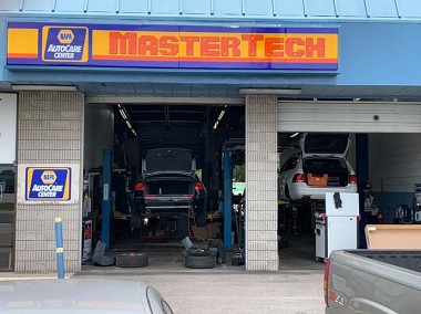 automotive garage service bays with two vehicles on lifts being serviced by mechanics in Virginia Beach